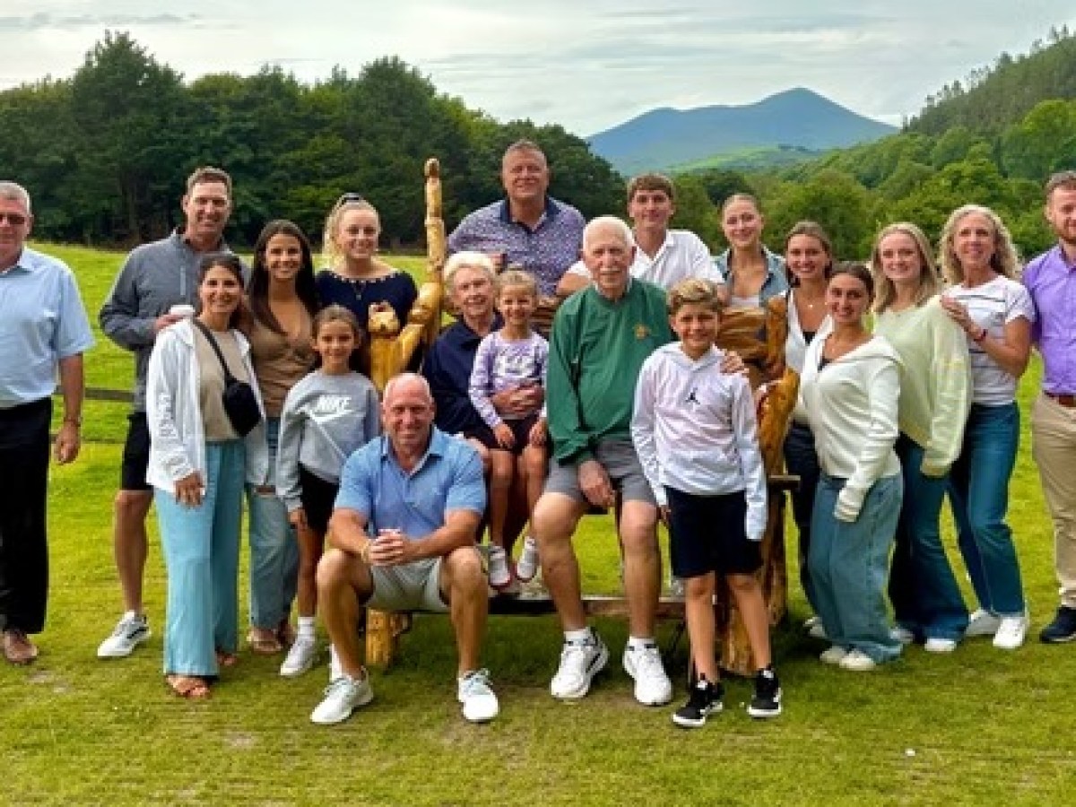 A group of people posing together outdoors on grass.